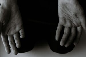 From above black and white of crop anonymous person showing lines on palms of hands