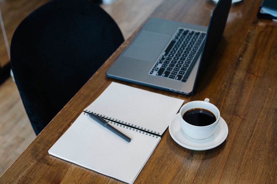 Notebook e café em mesa, ilustrando preparação para consulta por telemedicina